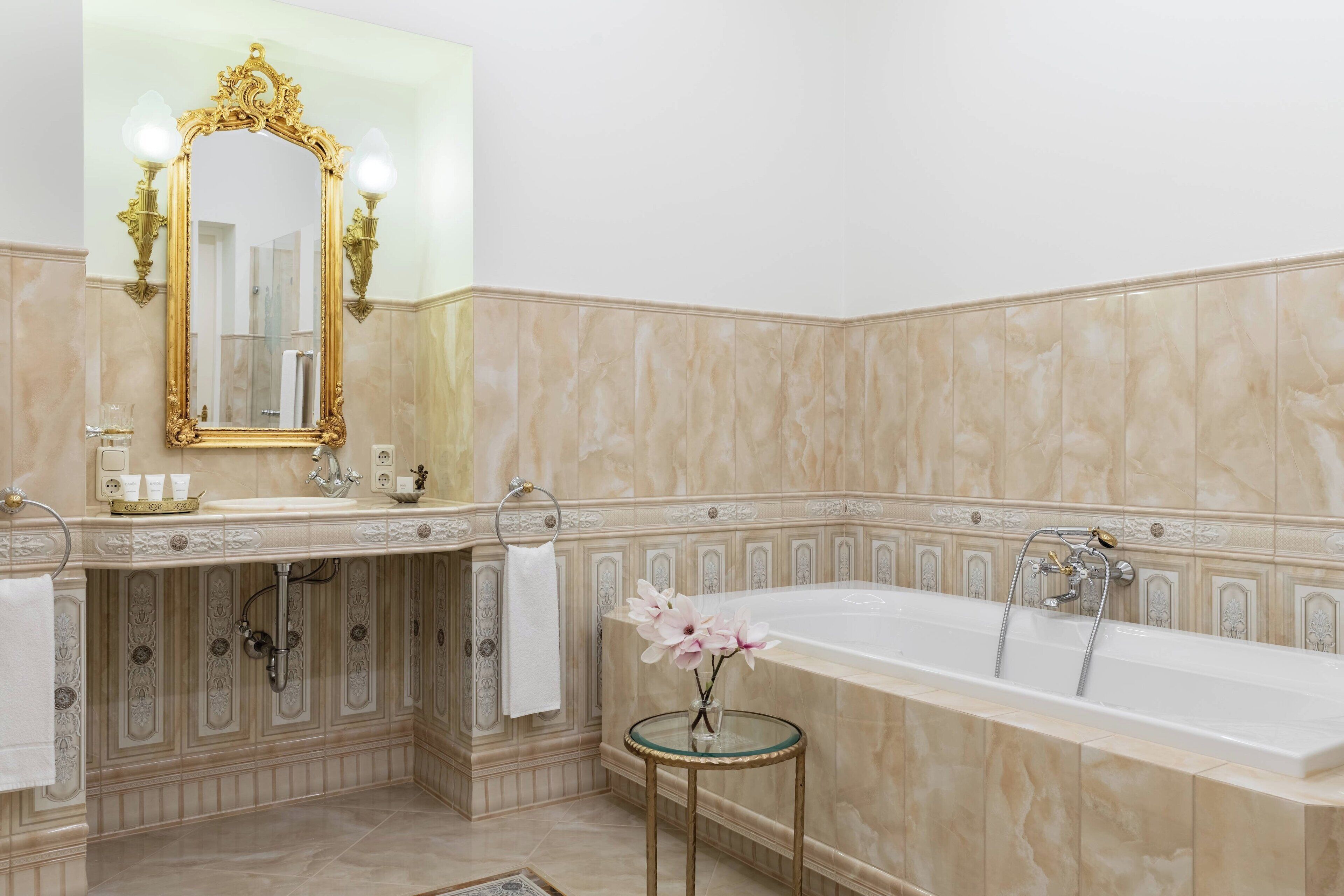 A luxurious bathroom with a large bathtub, a vanity with a mirror, and a small round table with a vase of flowers.