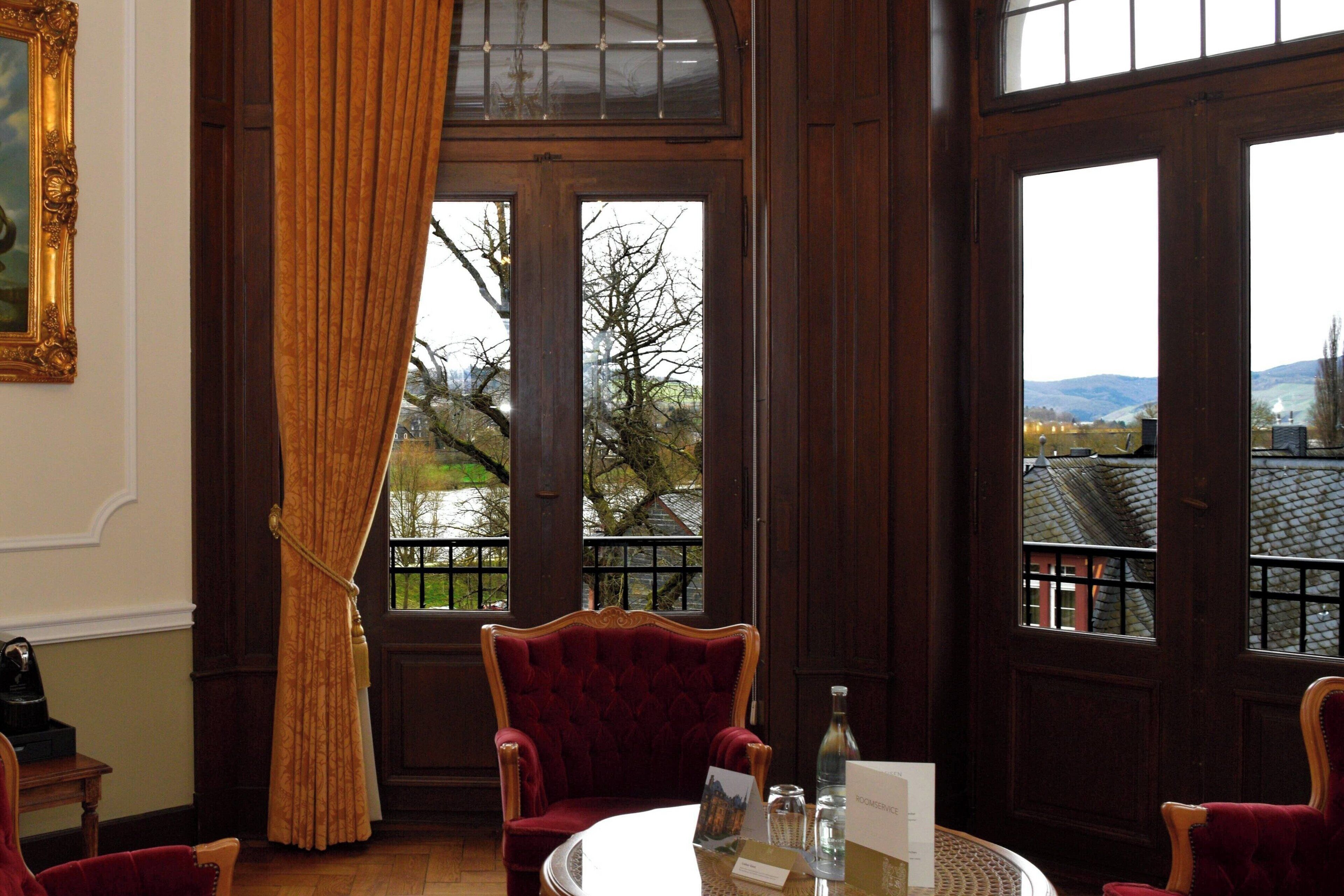 A room with a large window, a table with a bottle, and a chair.