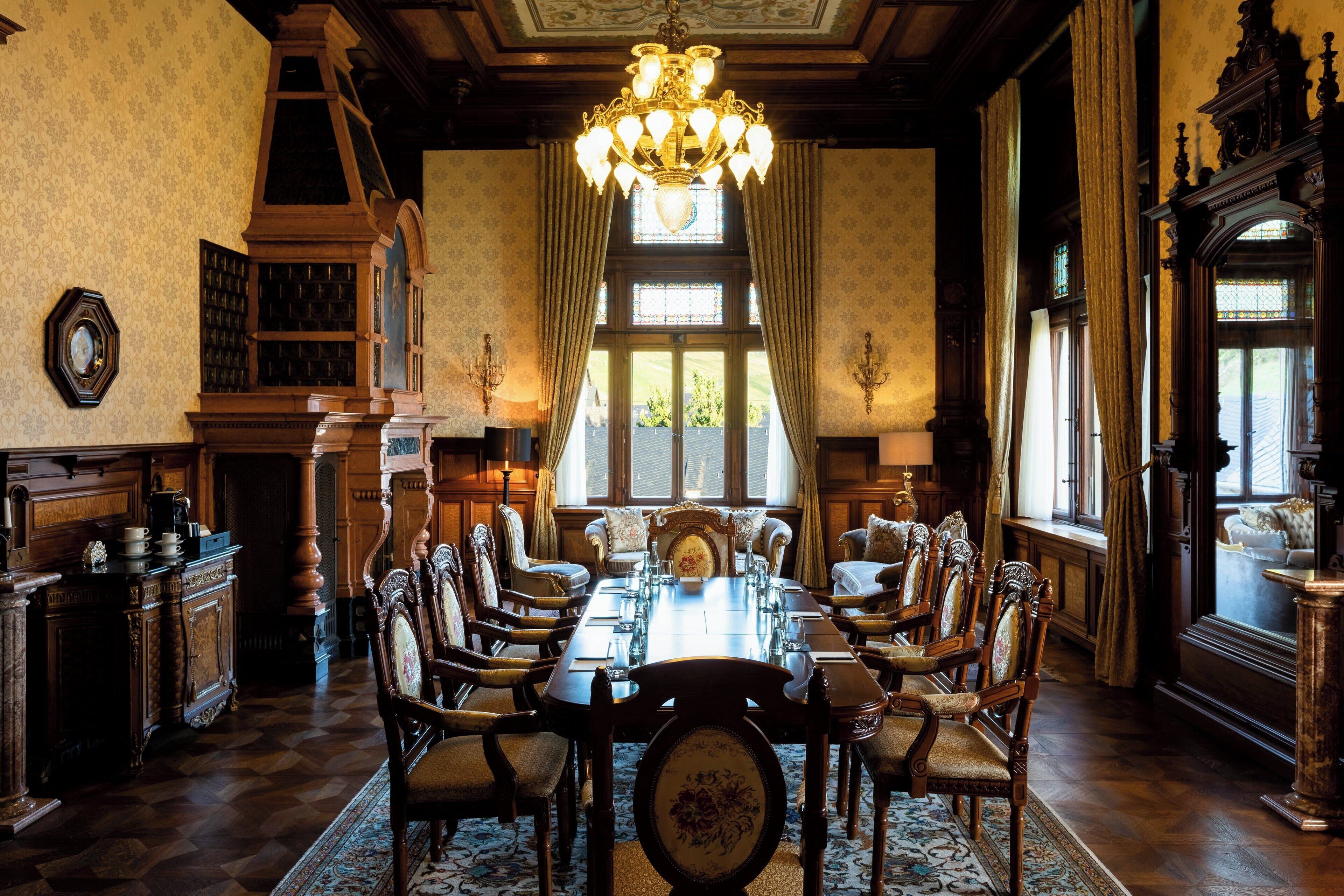 A formal dining room with a large wooden table, ornate chairs, and a chandelier.