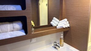 Un baño con tocador de madera, un espejo, un lavabo y toallas dobladas con cuidado.