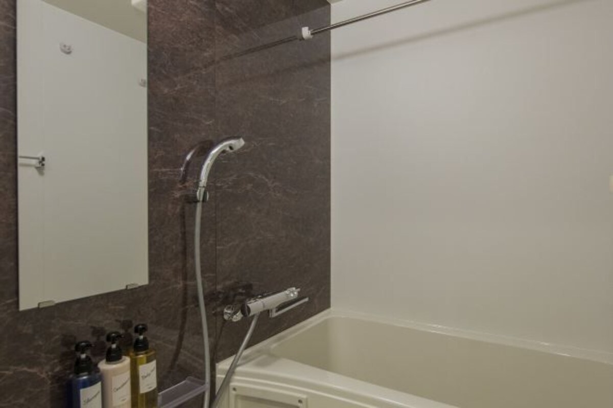 Une salle de bain moderne avec une baignoire, une douche et un mur en marbre.