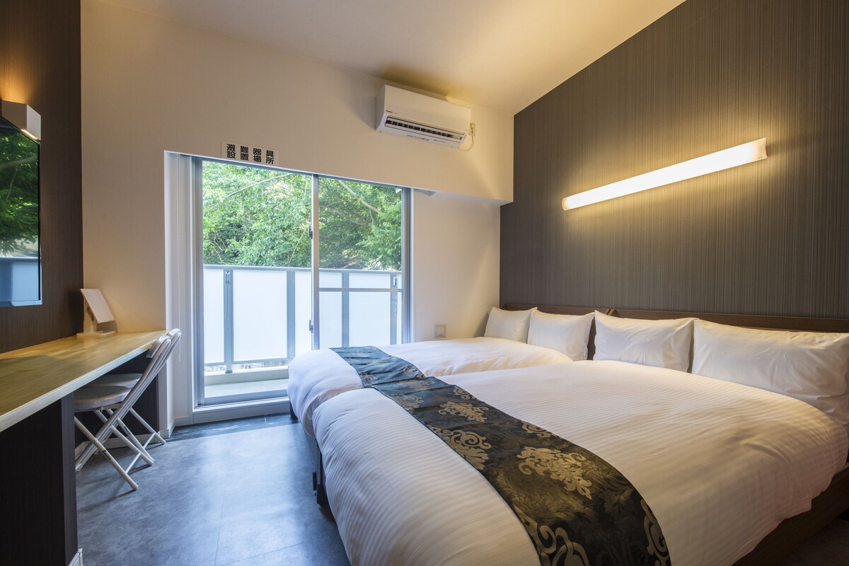 Een moderne hotelkamer met een groot bed, een bureau en een schuifdeur naar buiten.