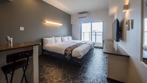 Een moderne hotelkamer met een groot bed, een bureau en een stoel. Een raam met uitzicht op de stad.