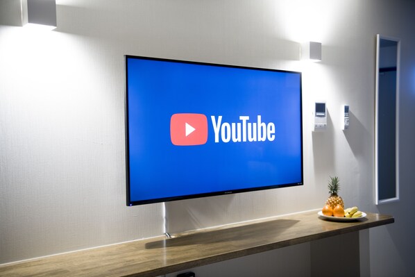 A flat-screen TV mounted on a wall displaying the YouTube logo.