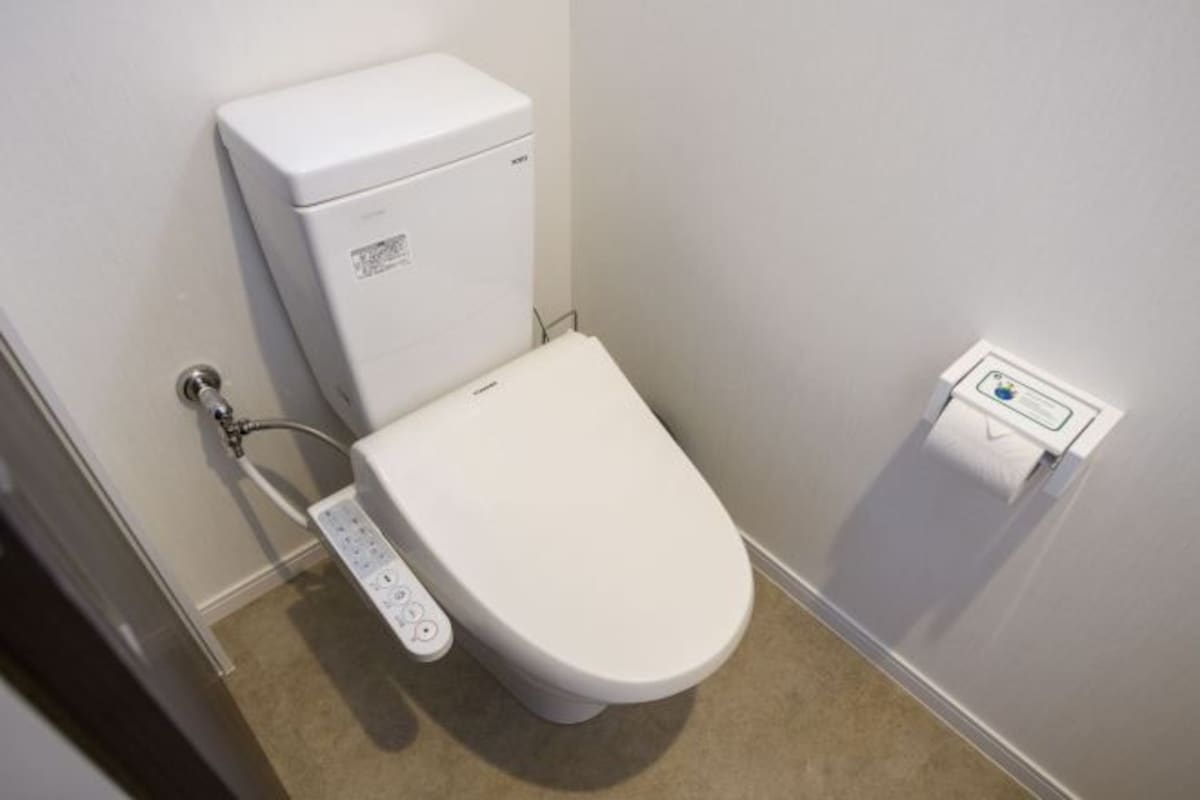 Des toilettes blanches dotées d’un panneau de commande et d’un bouton de chasse d’eau.