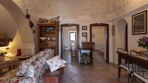 Un salon chaleureux avec un canapé à motifs floraux, des meubles en bois et un sol carrelé.