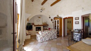 Une pièce rustique avec une cheminée, un canapé, une table à manger et un coin cuisine.