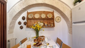 Une table de petit-déjeuner dressée avec des croissants, des pâtisseries et un vase rempli de fleurs jaunes.
