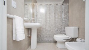 Casa de banho com lavatório branco, sanita e banheira.