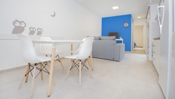 Um espaço de estar moderno e minimalista com área de jantar, sofá e cozinha.
