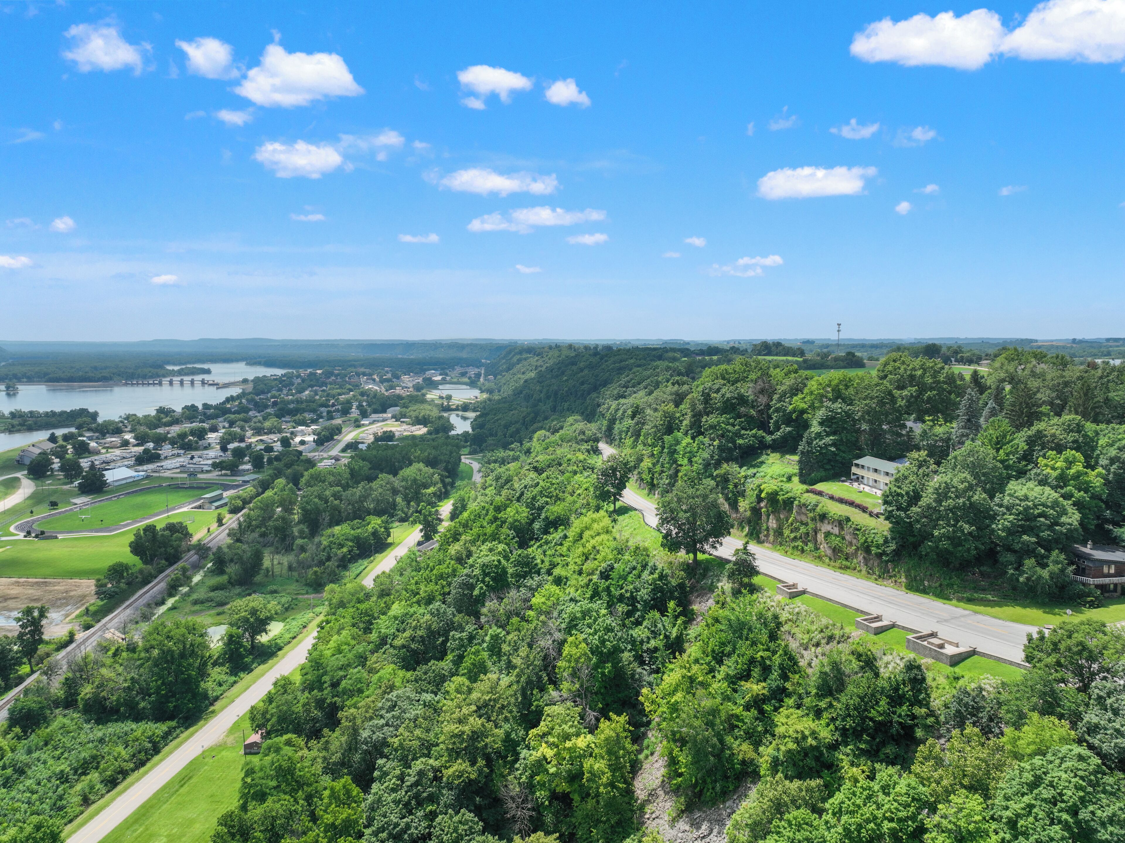 A lush green landscape with a river, a bridge, and a road.