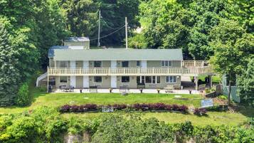A motel with a two-story structure, outdoor seating, and a view of the surrounding greenery.