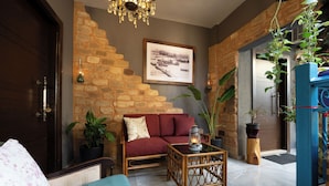 A cozy room with a wooden sofa, a small table, and a framed picture on the wall. - InnTown (Tyre)