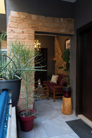 A cozy outdoor seating area with a brick archway, potted plants, and a wooden table with a lantern.
