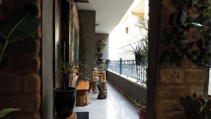 A corridor with potted plants, a wooden bench, and a view of a balcony with railings. - InnTown (Tyre)