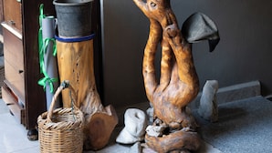 A wooden sculpture supporting a potted plant, a wicker basket, and a wooden cabinet with a green plant. - InnTown (Tyre)