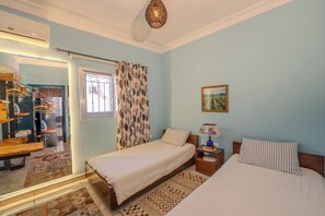 A bedroom with a bed, a nightstand, a lamp, and a window with curtains.