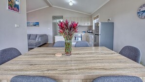 Uma sala de jantar com mesa de madeira, cadeiras e um vaso de flores.