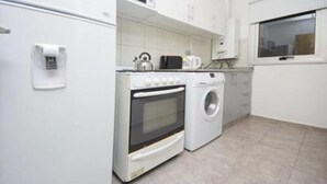Una cucina compatta con frigorifero, forno, microonde e lavatrice.
