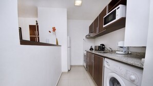 A compact kitchen with a built-in washing machine, a microwave, and a coffee maker. - Bvd. Illia Apartment AN4 (Córdoba)