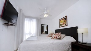 A neatly arranged bedroom with a bed, a television, a ceiling fan, and a bedside table with a lamp. - Bvd. Illia Apartment AN4 (Córdoba)