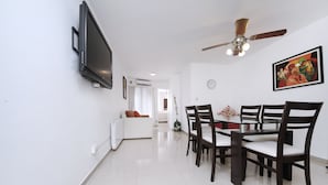 A modern living room with a flat-screen TV, a ceiling fan, a dining area with a table and chairs, and a large painting on the wall. - Bvd. Illia Apartment AN4 (Córdoba)