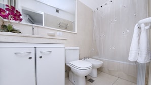 A modern bathroom with a toilet, bidet, and shower curtain. - Bvd. Illia Apartment AN4 (Córdoba)