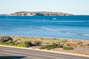 A coastal road with a clear view of the sea and a distant rocky island.