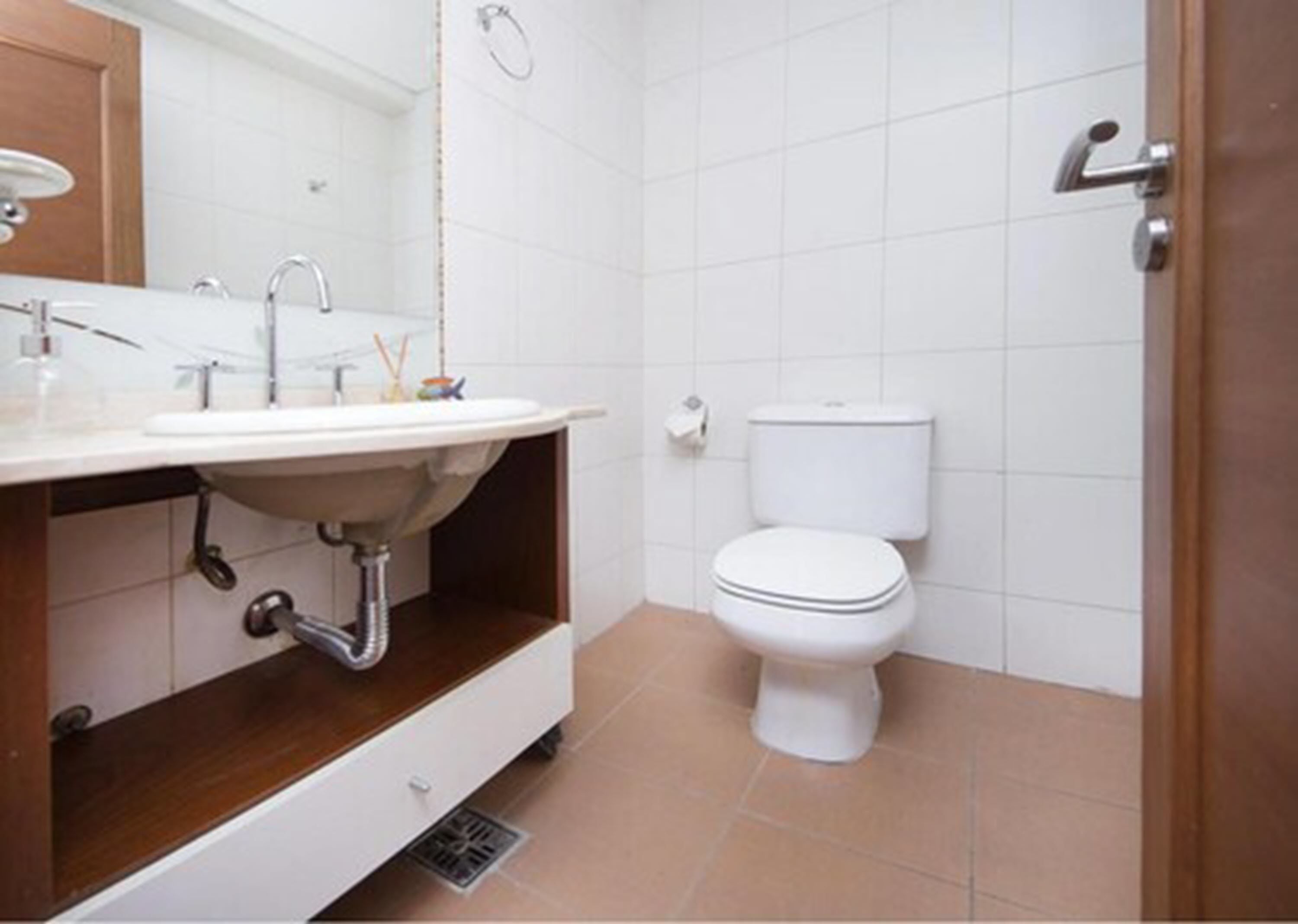 A bathroom with a white sink, mirror, and toilet.