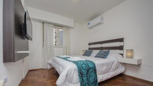 A bedroom with a bed, a TV mounted on the wall, and a window with curtains. - Obispo Salguero 21A (Córdoba)
