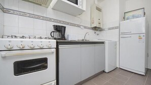 A kitchen with white cabinets, a stove, a coffee maker, and a refrigerator. - Obispo Salguero 21A (Córdoba)