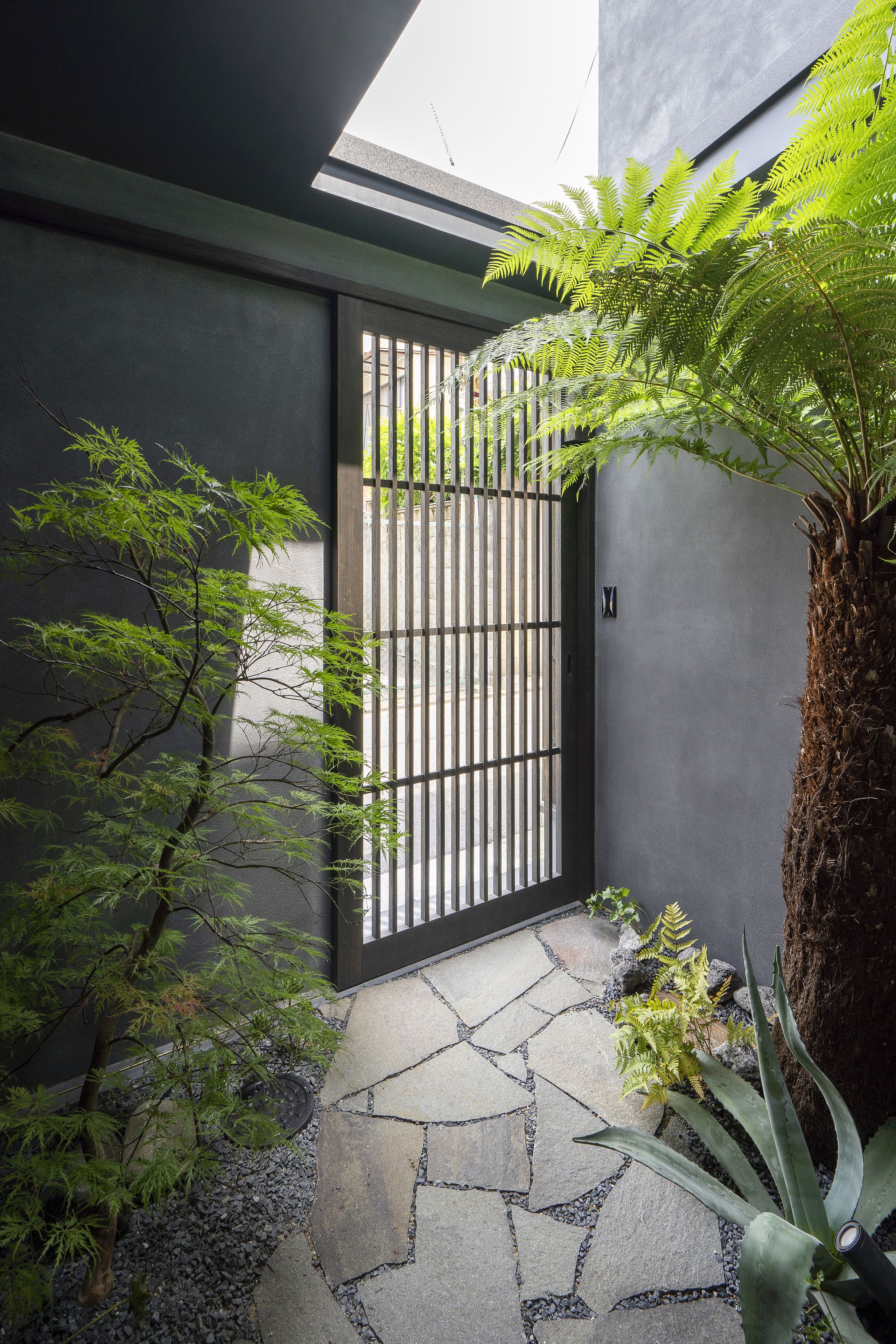 A modern building with a stone pathway leading to a gated entrance.