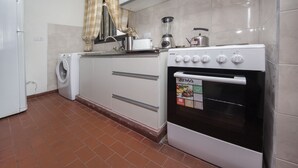 A compact kitchen with a washing machine, a stove, and a blender. - Dean Funes X22 (Córdoba)
