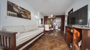 A living room with a sofa, a TV, a wooden floor, and a painting on the wall. - Dean Funes X22 (Córdoba)