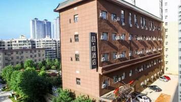 A multi-story hotel with a brown facade, multiple balconies, and a visible entrance with a sign.