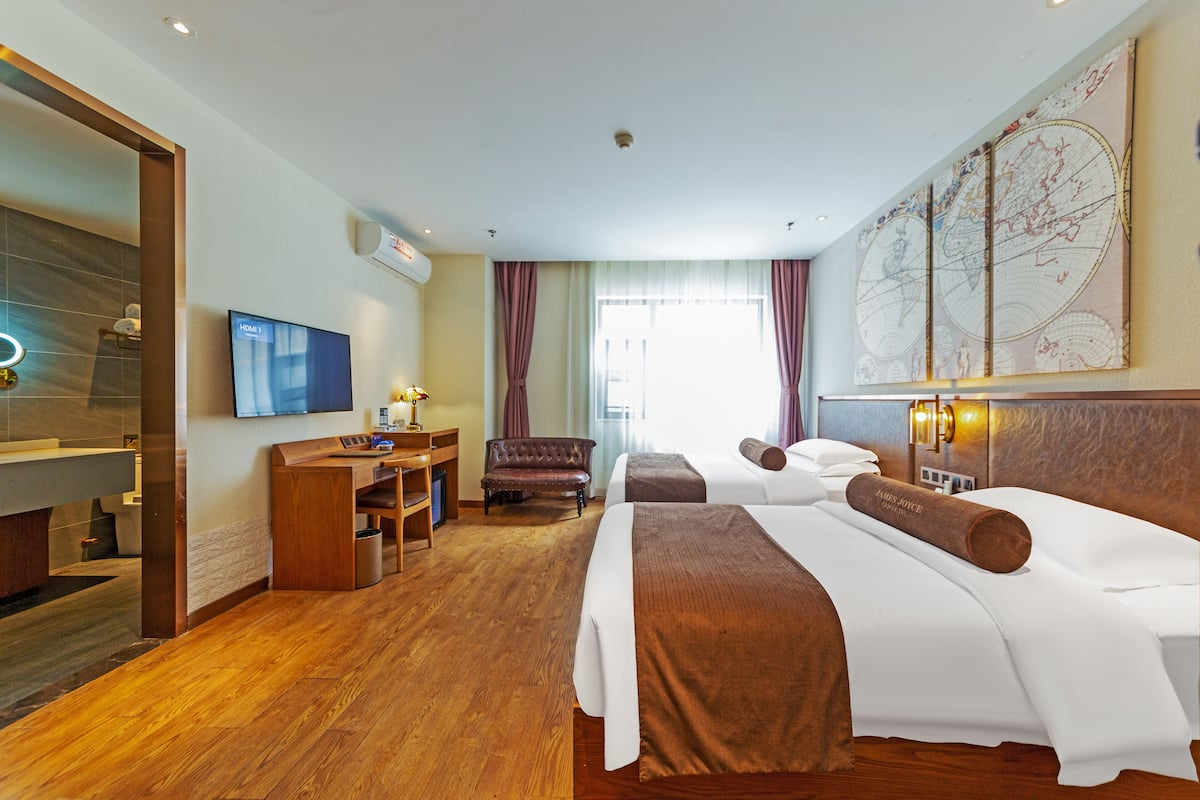 A hotel room with two beds, a desk, a TV, and a large wall map.