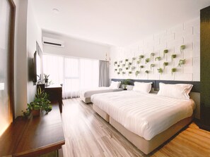 A modern hotel room with a large bed, a desk, and a wall-mounted plant display. - The Atelier (Kota Kinabalu)