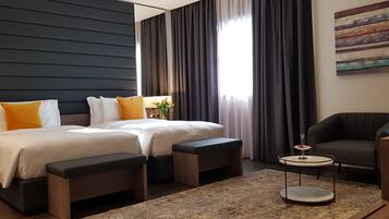 Una habitación de hotel moderna con una cama grande, dos mesitas de noche, una pequeña mesa redonda y un sofá.