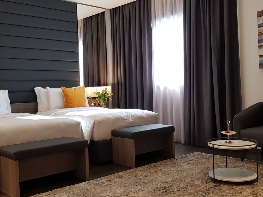 Una habitación de hotel moderna con una cama grande, dos mesitas de noche, una pequeña mesa redonda y un sofá.