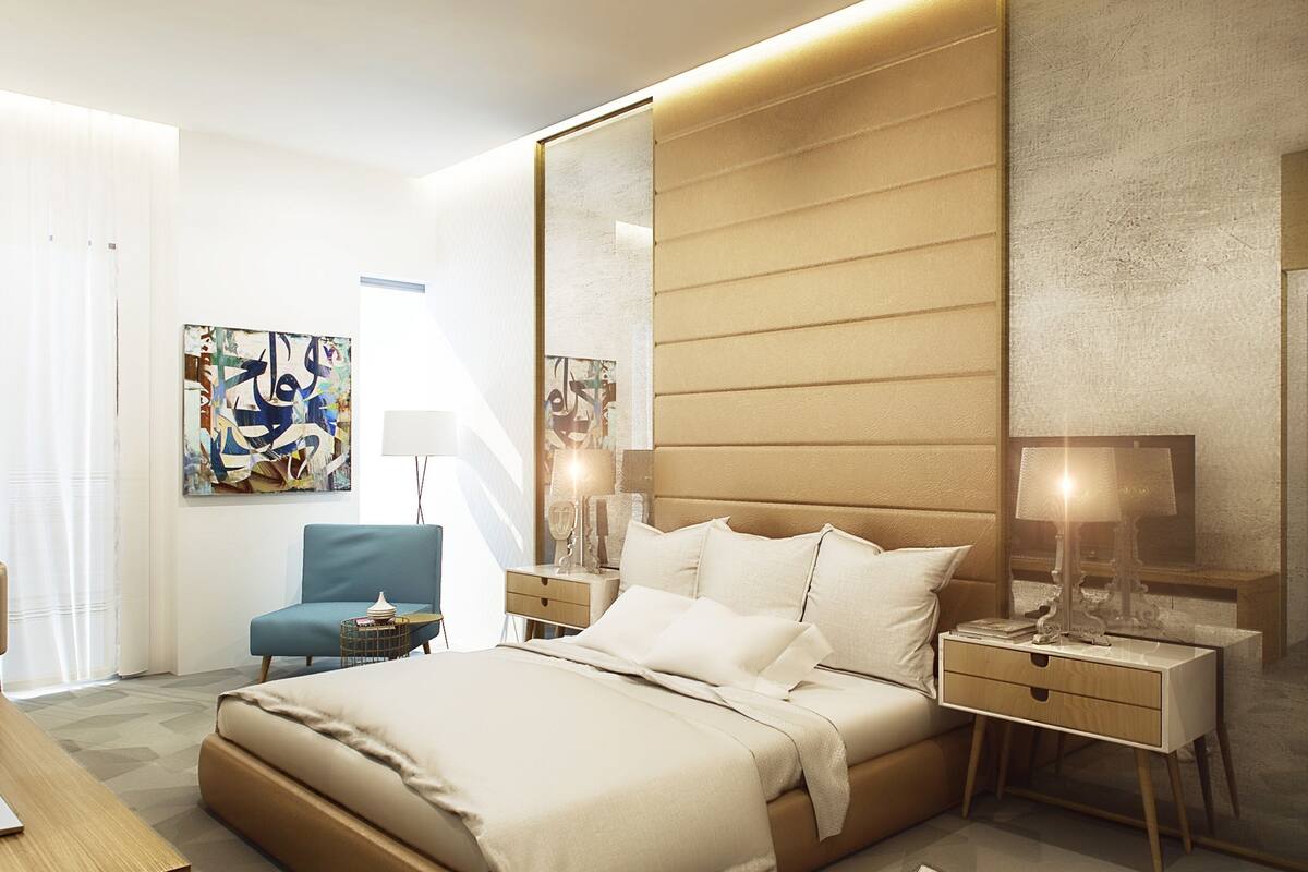 Un dormitorio moderno con una cama grande, mesitas de noche, una silla y obras de arte en las paredes.