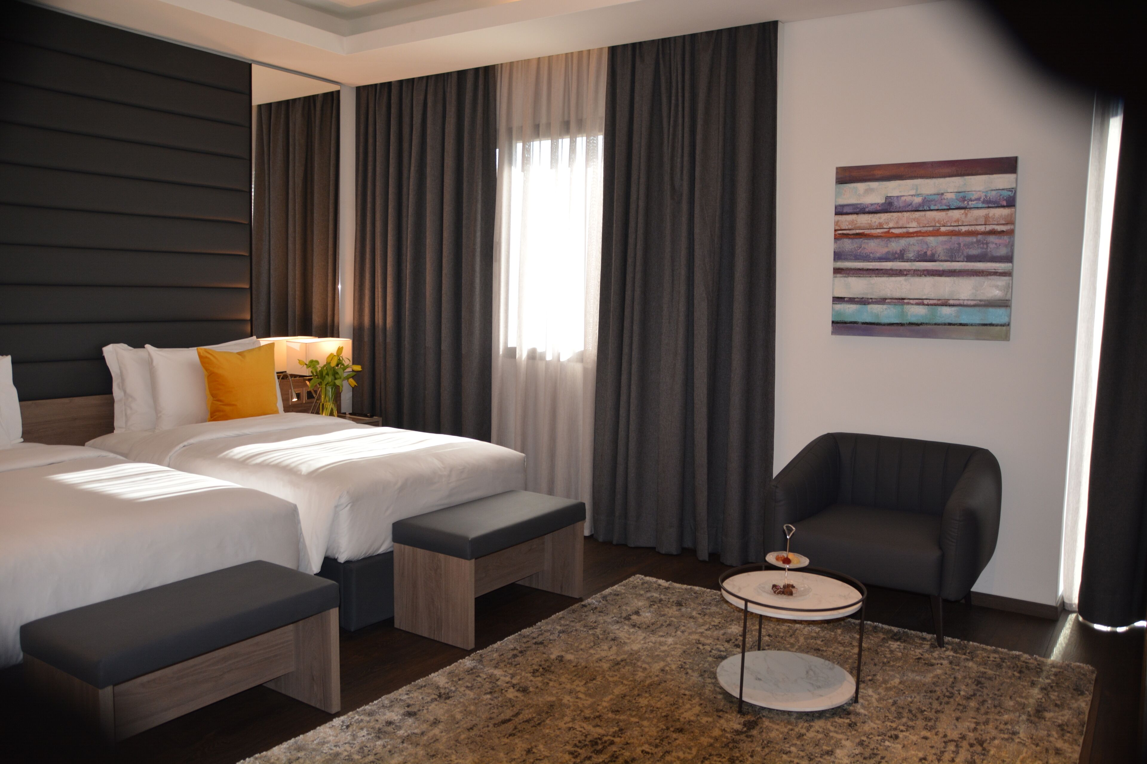Ein modernes Hotelzimmer mit einem großen Bett, einer Bank, einem kleinen Tisch und einer Couch.