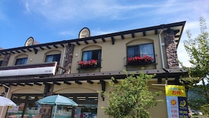 Ett hotell med en traditionell arkitektur, med en balkong prydd med blomlådor och en klarblå himmel i bakgrunden.