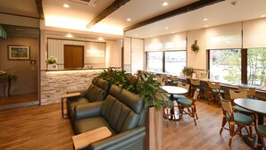 A restaurant with wooden flooring, green leather seating, and wooden tables with green chairs.