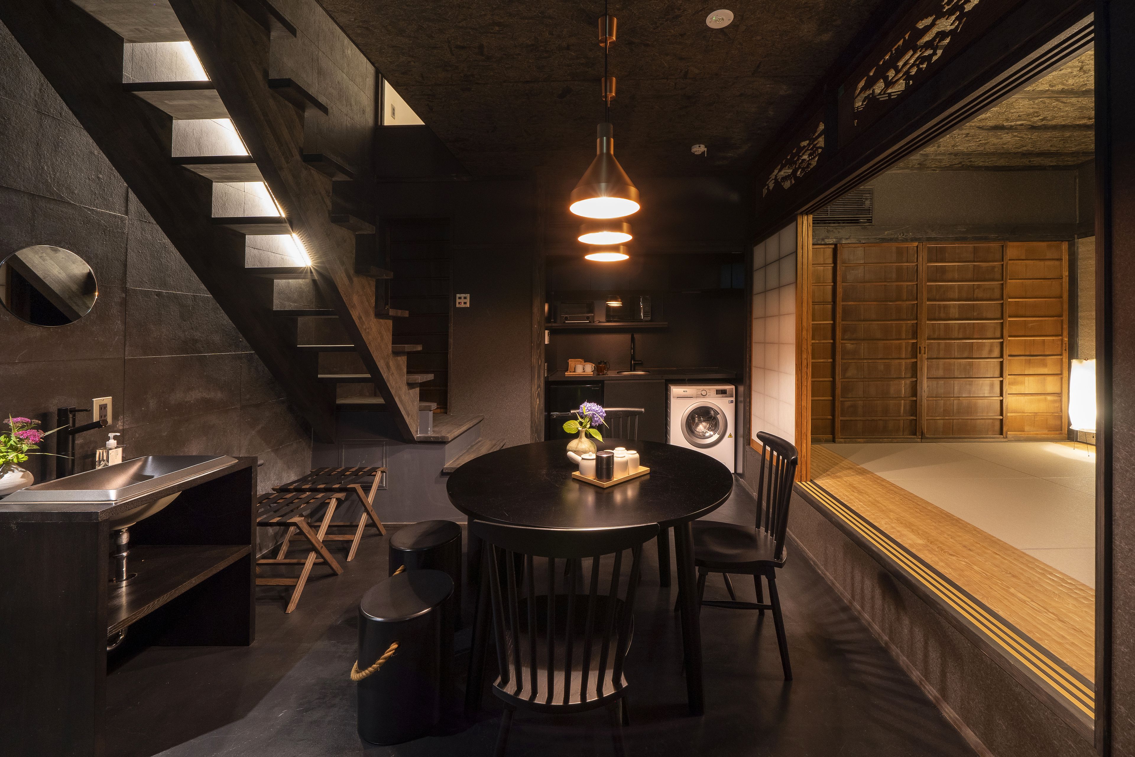 A modern kitchen with a round dining table, built-in appliances, and a staircase.