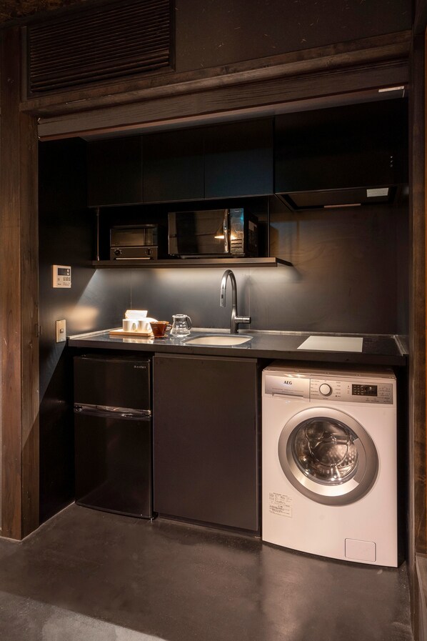 A compact kitchen with a built-in dishwasher, a washing machine, a microwave, and a sink.