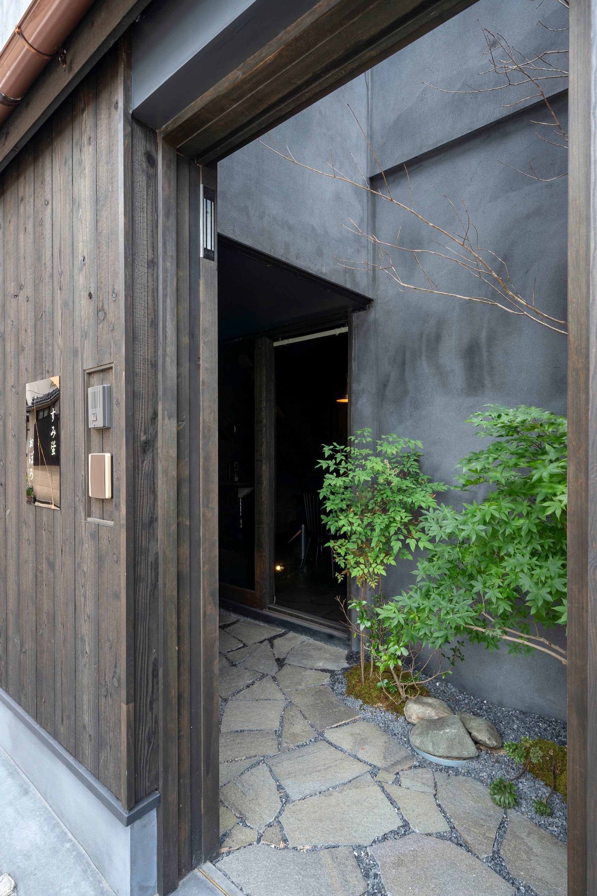 A wooden exterior with a stone pathway leading to a dark interior.