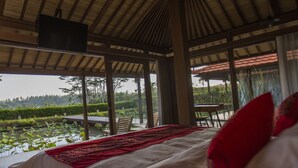 Ein Zimmer mit einem Bett, einem Tisch und Stühlen mit Blick auf einen Teich.