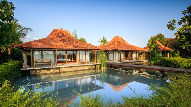 Ein Resort mit zwei Gebäuden, einem Pool und üppiger Bepflanzung.