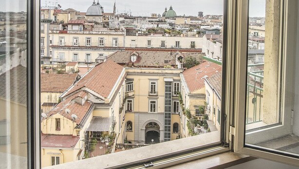 Vista desde una ventana con vistas a un paisaje urbano que incluye edificios históricos y estructuras con cúpulas.