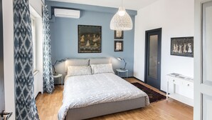 Un dormitorio con cama, mesitas de noche, una lámpara colgante y obras de arte en las paredes.